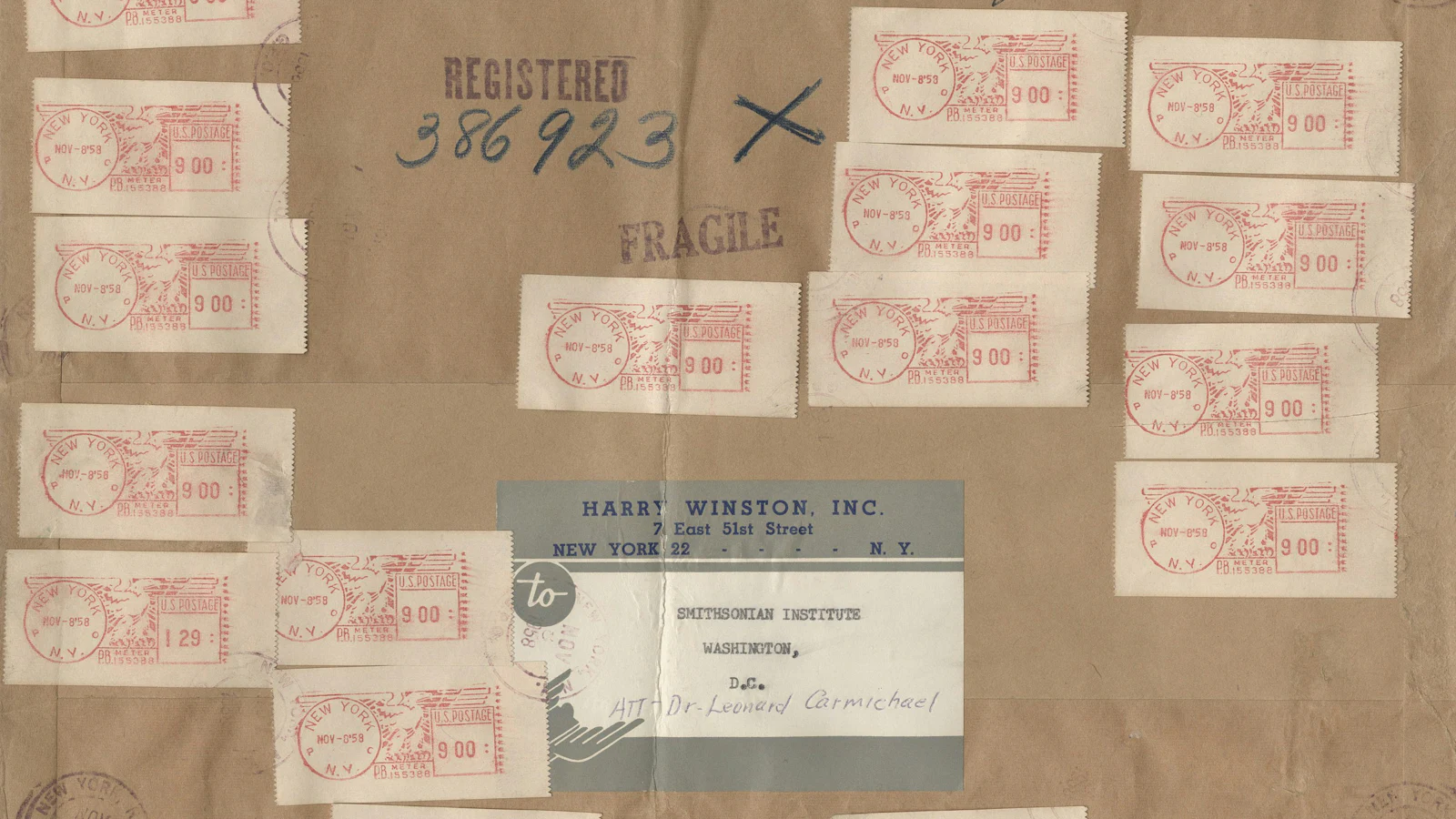 A registered-mail wrapper covered in postage meter stamps, marked REGISTERED and FRAGILE with its number and both parties named, the whole handling chain written on the outside