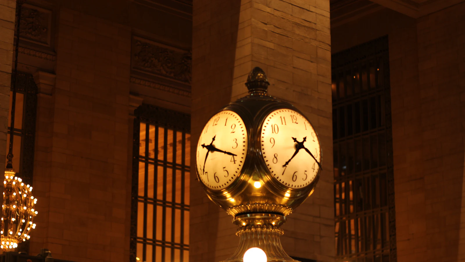A brass station clock with several faces on one pillar, every face driven by the same movement: one mechanism checking itself, the way one person writes the criteria and then reviews against them
