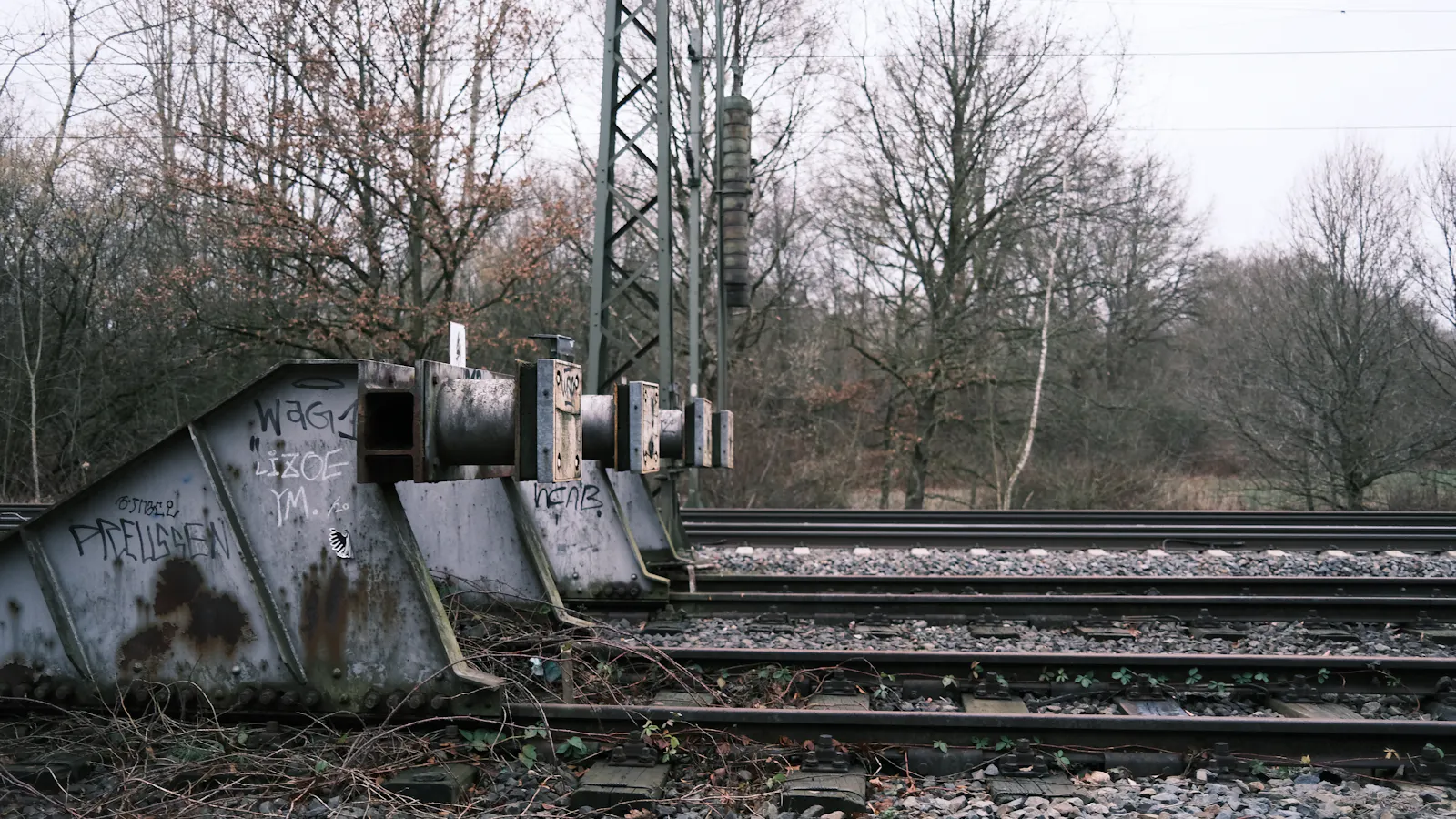 A steel buffer stop at the end of a railway siding beside the running lines, placed where the track was built to end rather than wherever the train happens to halt