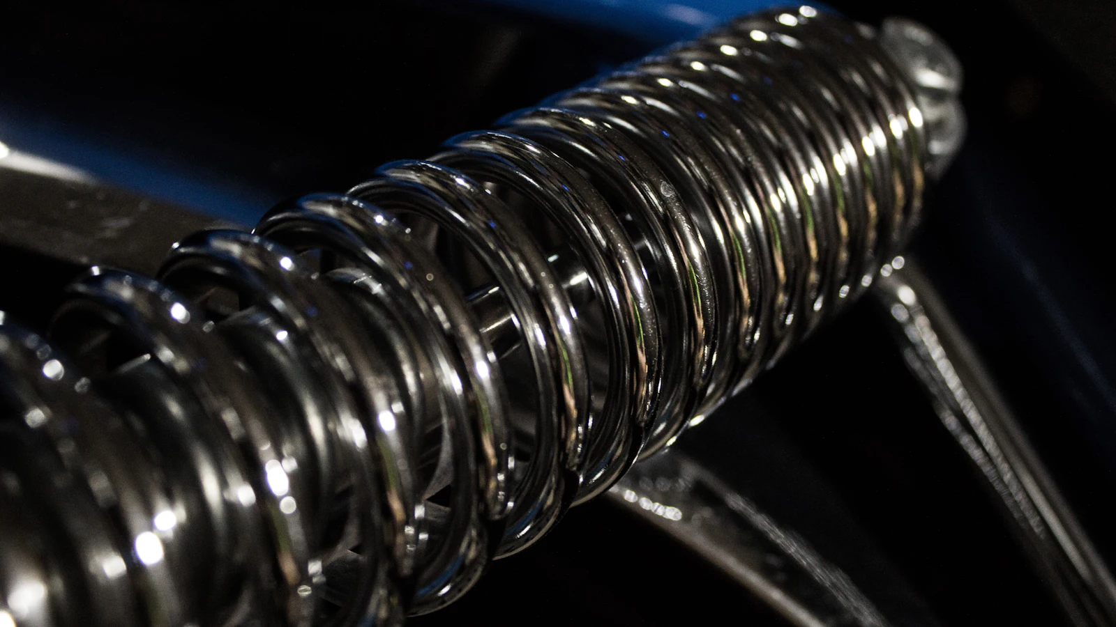 A chromed coil spring wound over a damper, a component whose whole job is to resist and whose rate is specified rather than wished away